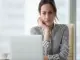 Woman-at-desk-frowning-at-her-white-laptop-1